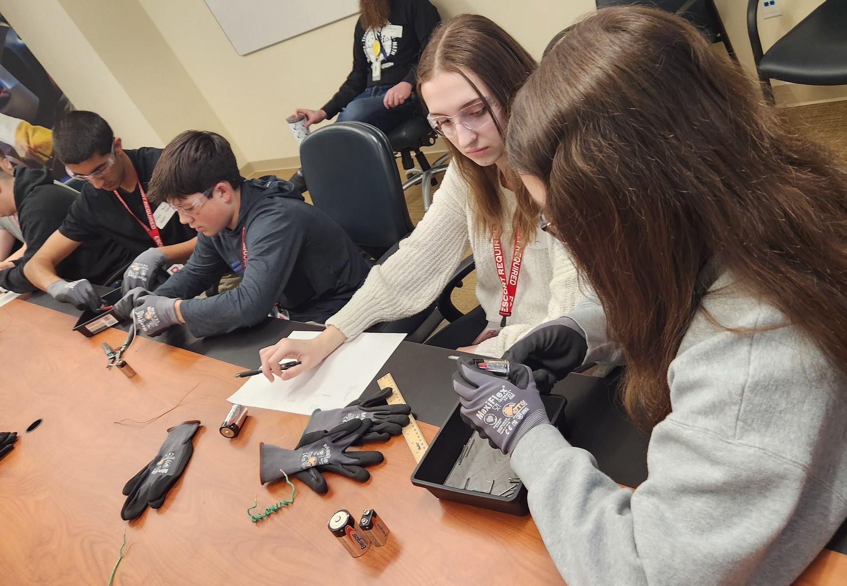 Students practice electromagnetic experimentation using wires, nails, and batteries